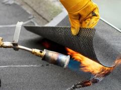 Installation of roofing material using a torch